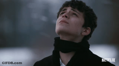 A Man With A Scarf Around His Neck Is Looking Up With A Netflix Logo In The Corner GIF
