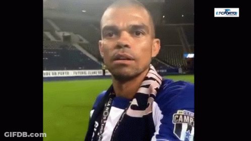 A Man With A Scarf Around His Neck Is Wearing A Blue And White Shirt With The Number 14 On It . GIF