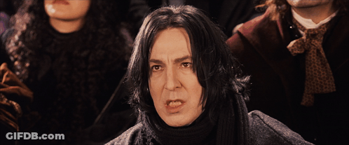 A Man With A Scarf Around His Neck Stands In Front Of A Group Of People GIF