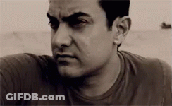 A Man With A Serious Look On His Face Is Wearing A Black Shirt . GIF