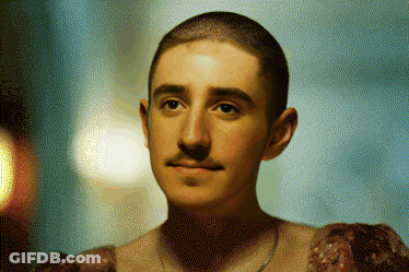 A Man With A Shaved Head And A Mustache Is Wearing A Dress GIF
