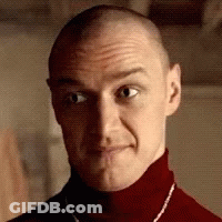 A Man With A Shaved Head Is Wearing A Red Turtleneck And A Necklace . GIF