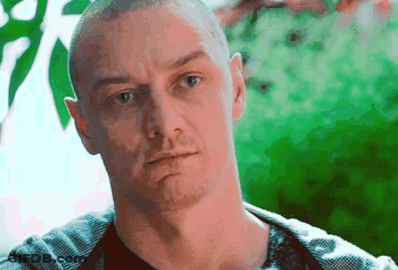 A Man With A Shaved Head Looks At The Camera With A Serious Look On His Face GIF