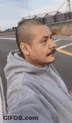 A Man With A Shaved Head Wearing A Grey Sweatshirt GIF