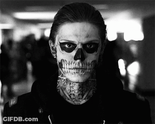 A Man With A Skull Painted On His Face And A Tattoo On His Neck Is In A Black And White Photo . GIF