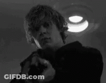 A Man With A Skull Painted On His Face Is Pointing A Gun . GIF