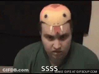 A Man With A Snake Mask On His Head Is Making A Funny Face . GIF