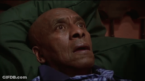 A Man With A Surprised Look On His Face Is Laying On A Green Blanket GIF