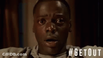 A Man With A Surprised Look On His Face Is Sitting On A Couch In A Room . GIF