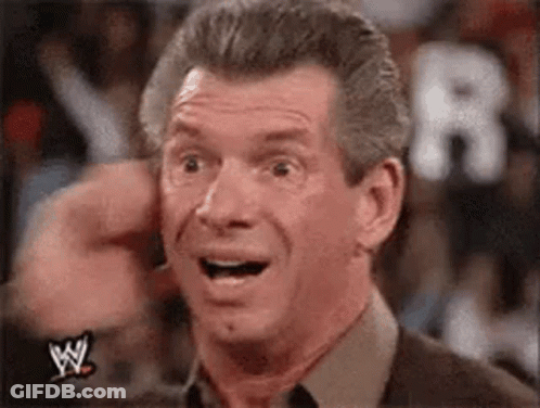 A Man With A Surprised Look On His Face Is Wearing A Wrestling Shirt And Tie . GIF