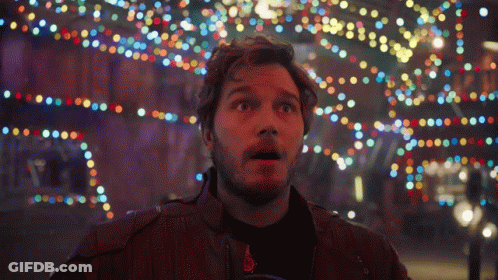 A Man With A Surprised Look On His Face Stands In Front Of A Bunch Of Colorful Lights GIF
