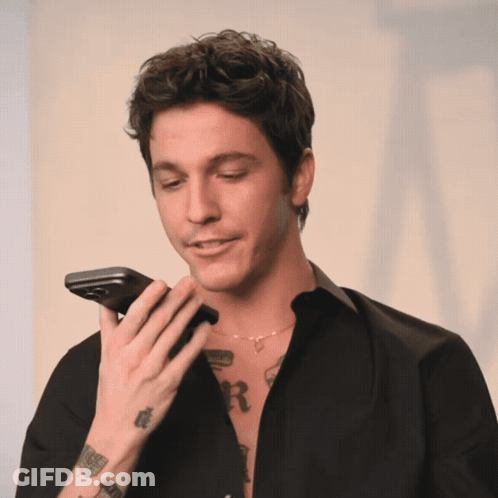 A Man With A Tattoo Of The Letter R On His Chest Holds A Cell Phone GIF