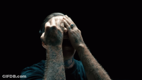 A Man With A Tattoo On His Arm Covering His Face GIF