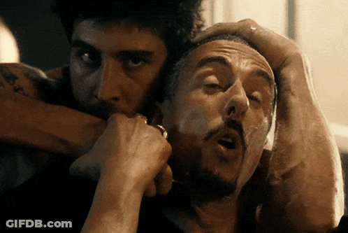 A Man With A Tattoo On His Arm Holds Another Man 'S Head In His Hands GIF