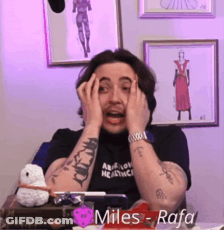 A Man With A Tattoo On His Arm Is Covering His Face With His Hands While Wearing A Black Shirt That Says Miles Rafa GIF