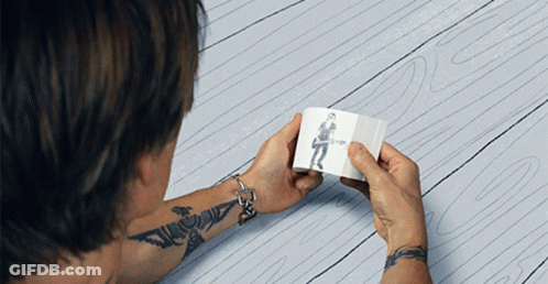 A Man With A Tattoo On His Arm Is Holding A Drawing Of A Man Playing A Guitar GIF