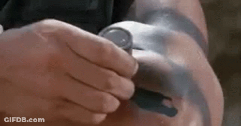 A Man With A Tattoo On His Arm Is Holding A Watch . GIF