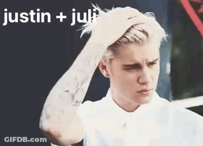 A Man With A Tattoo On His Arm Is Holding His Hair . GIF