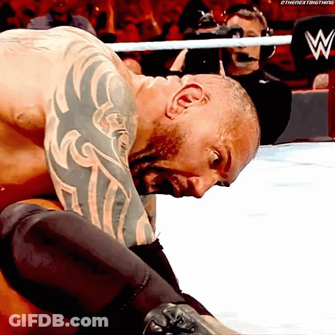 A Man With A Tattoo On His Arm Is Kneeling Down In A Wrestling Ring With A W Logo In The Background GIF