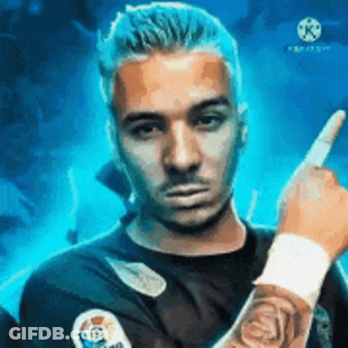 A Man With A Tattoo On His Arm Is Pointing At The Camera With His Finger . GIF