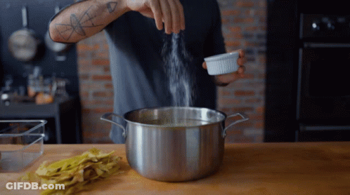 A Man With A Tattoo On His Arm Is Pouring Salt Into A Pot Of Water GIF