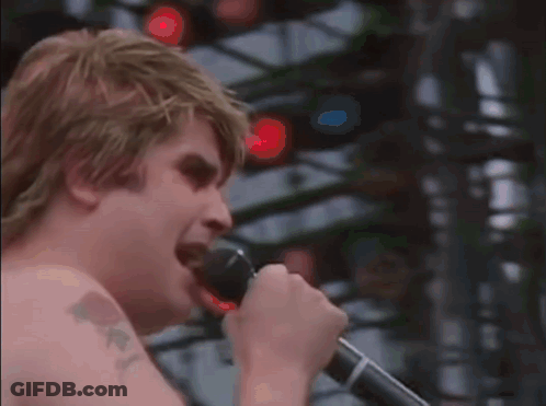 A Man With A Tattoo On His Arm Is Singing Into A Microphone .. GIF