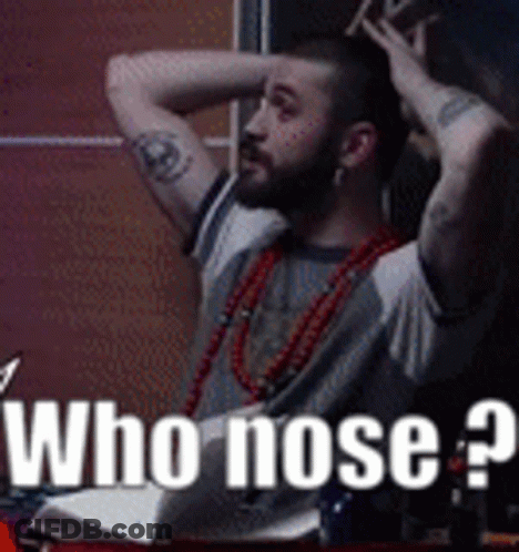 A Man With A Tattoo On His Arm Is Sitting At A Table With His Hands On His Head And The Words " Who Nose " On The Bottom GIF