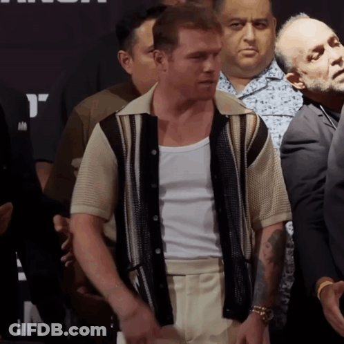 A Man With A Tattoo On His Arm Is Standing In A Crowd Of People GIF