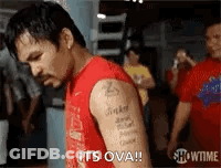 A Man With A Tattoo On His Arm Is Standing In A Gym And Says `` It 'S Ova '' . GIF