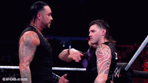 A Man With A Tattoo On His Arm Is Standing In A Ring With Two Other Men GIF