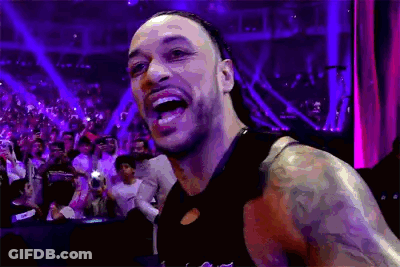 A Man With A Tattoo On His Arm Is Standing In Front Of A Crowd And Smiling . GIF