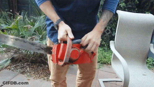 A Man With A Tattoo On His Arm Is Using A Chainsaw GIF