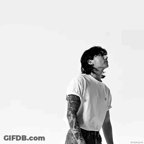 A Man With A Tattoo On His Arm Is Wearing A White T-Shirt With The Letter K On It GIF