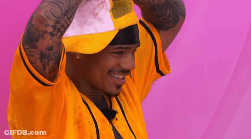 A Man With A Tattoo On His Arm Is Wearing A Yellow Shirt And A White Hat GIF