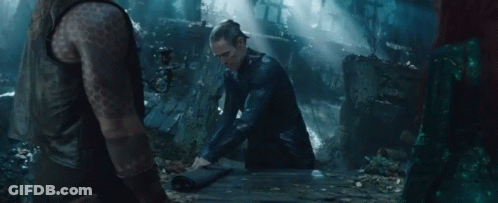 A Man With A Tattoo On His Arm Sits On A Wooden Table In A Dark Forest GIF