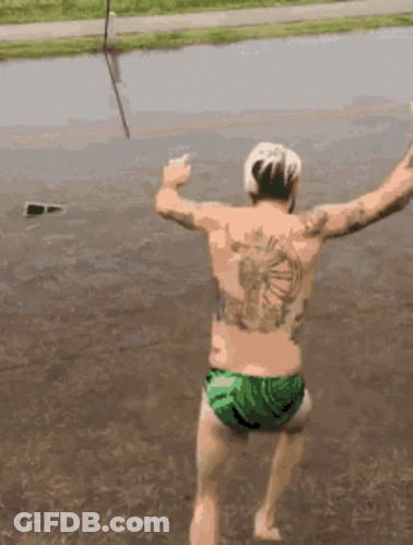 A Man With A Tattoo On His Back Jumping Into A Body Of Water GIF