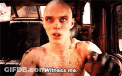 A Man With A Tattoo On His Chest Is Sitting In A Car And Saying Witness Me . GIF