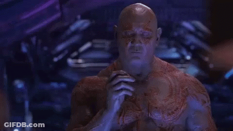 A Man With A Tattoo On His Chest Is Sitting In A Dark Room . GIF