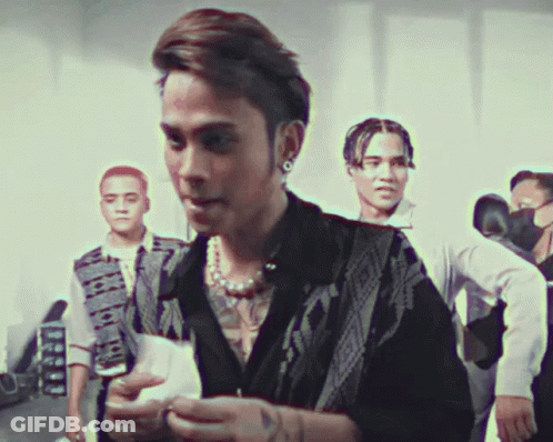 A Man With A Tattoo On His Chest Is Standing In A Crowd GIF
