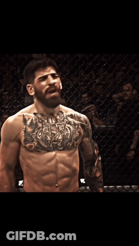 A Man With A Tattoo On His Chest Is Standing In Front Of A Sign That Says Pro.com GIF