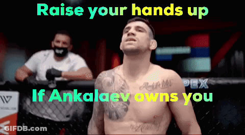 A Man With A Tattoo On His Chest Stands In Front Of A Sign That Says Raise Your Hands Up If Ankalev Owns You GIF
