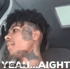 A Man With A Tattoo On His Face Is Sitting In A Car With The Words `` Yeah ... Aight '' Written Above Him . GIF