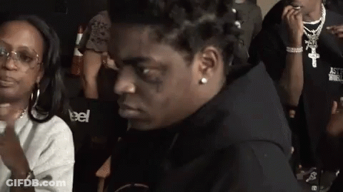 A Man With A Tattoo On His Face Is Sitting Next To A Woman Wearing A Sweatshirt That Says Astroworld GIF