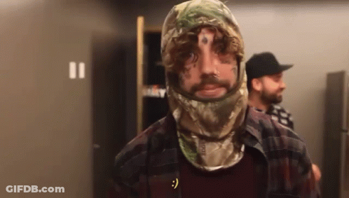 A Man With A Tattoo On His Face Wears A Camo Hood GIF