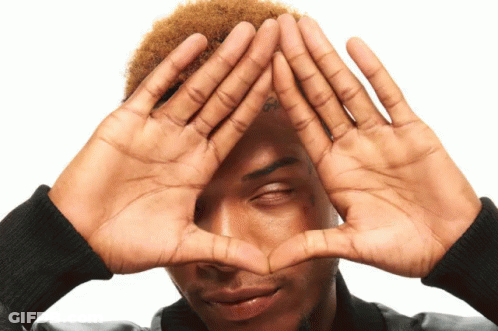 A Man With A Tattoo On His Forehead Makes A Heart With His Hands GIF
