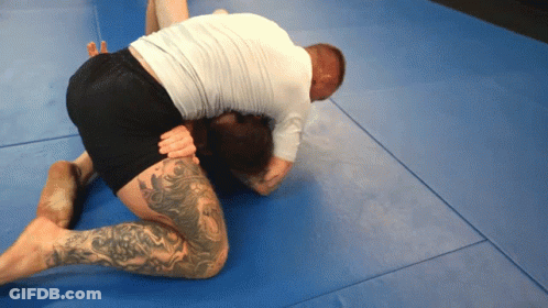 A Man With A Tattoo On His Leg Is Kneeling Down On A Blue Mat GIF