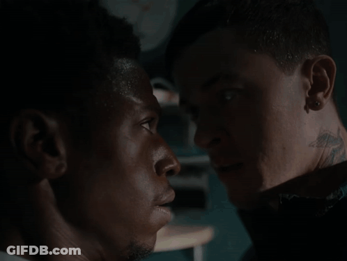 A Man With A Tattoo On His Neck Is Looking At Another Man GIF