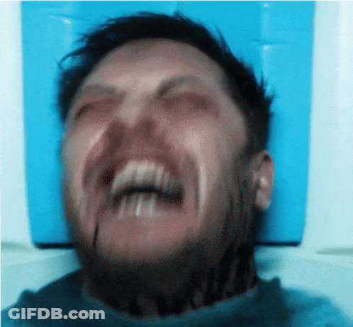A Man With A Tattoo On His Neck Is Making A Funny Face With His Mouth Open . GIF