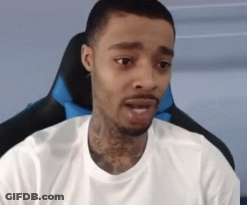 A Man With A Tattoo On His Neck Is Sitting In A Chair And Looking At The Camera . GIF
