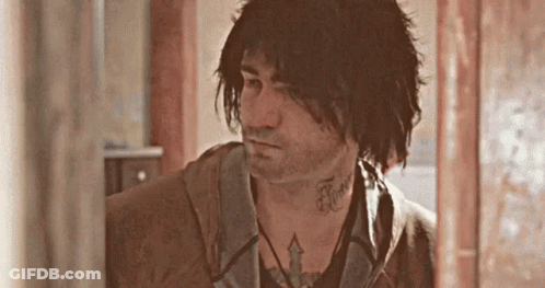 A Man With A Tattoo On His Neck Is Standing In A Room . GIF
